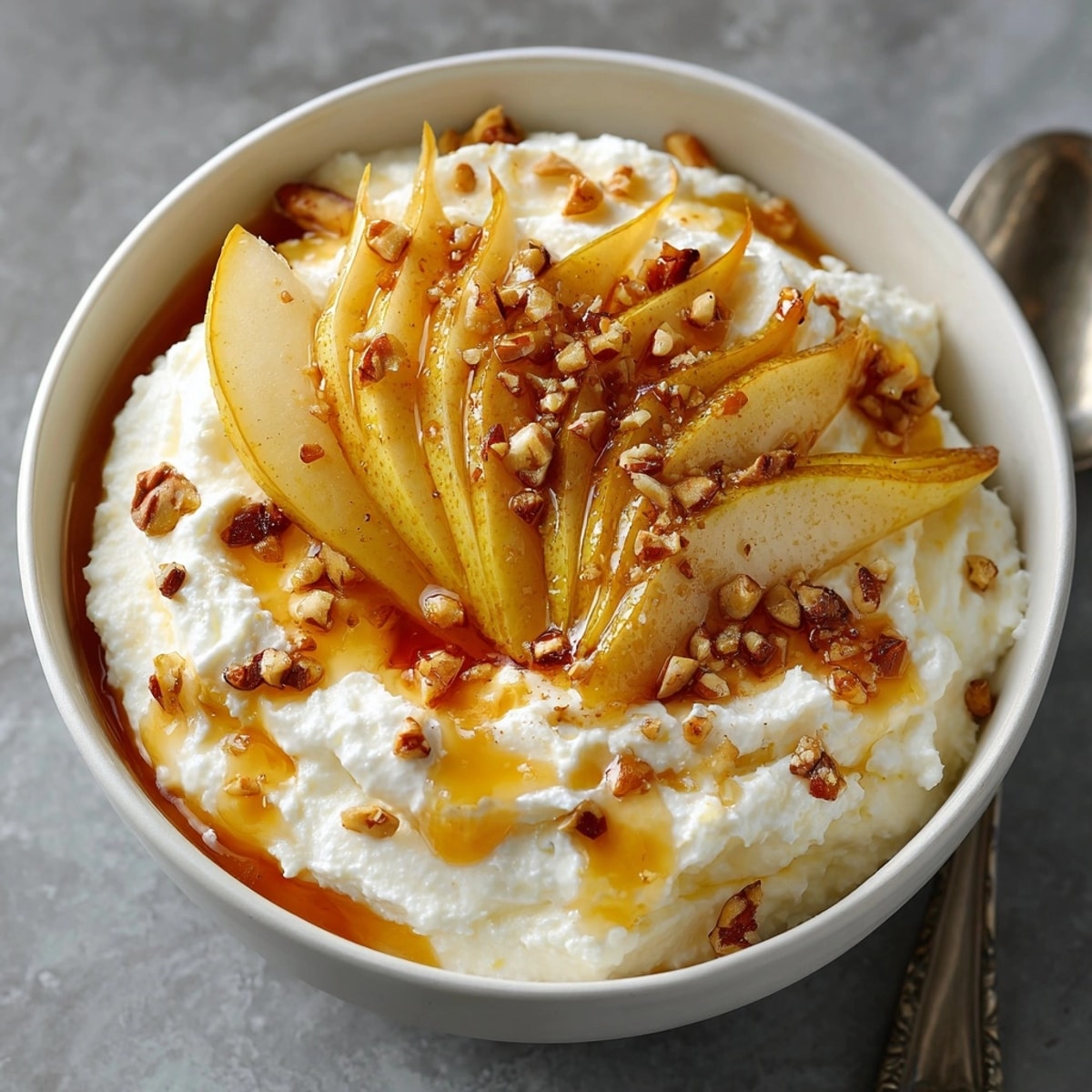 Sweet Ricotta with Fresh Fruit topped with honey and pears in a white bowl.