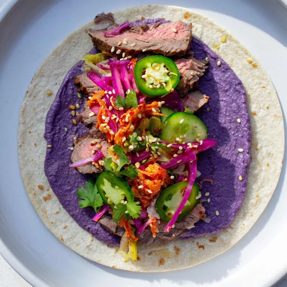 Vibrant Global Street-Food Fusion Tacos topped with ube crema and fresh vegetables.  