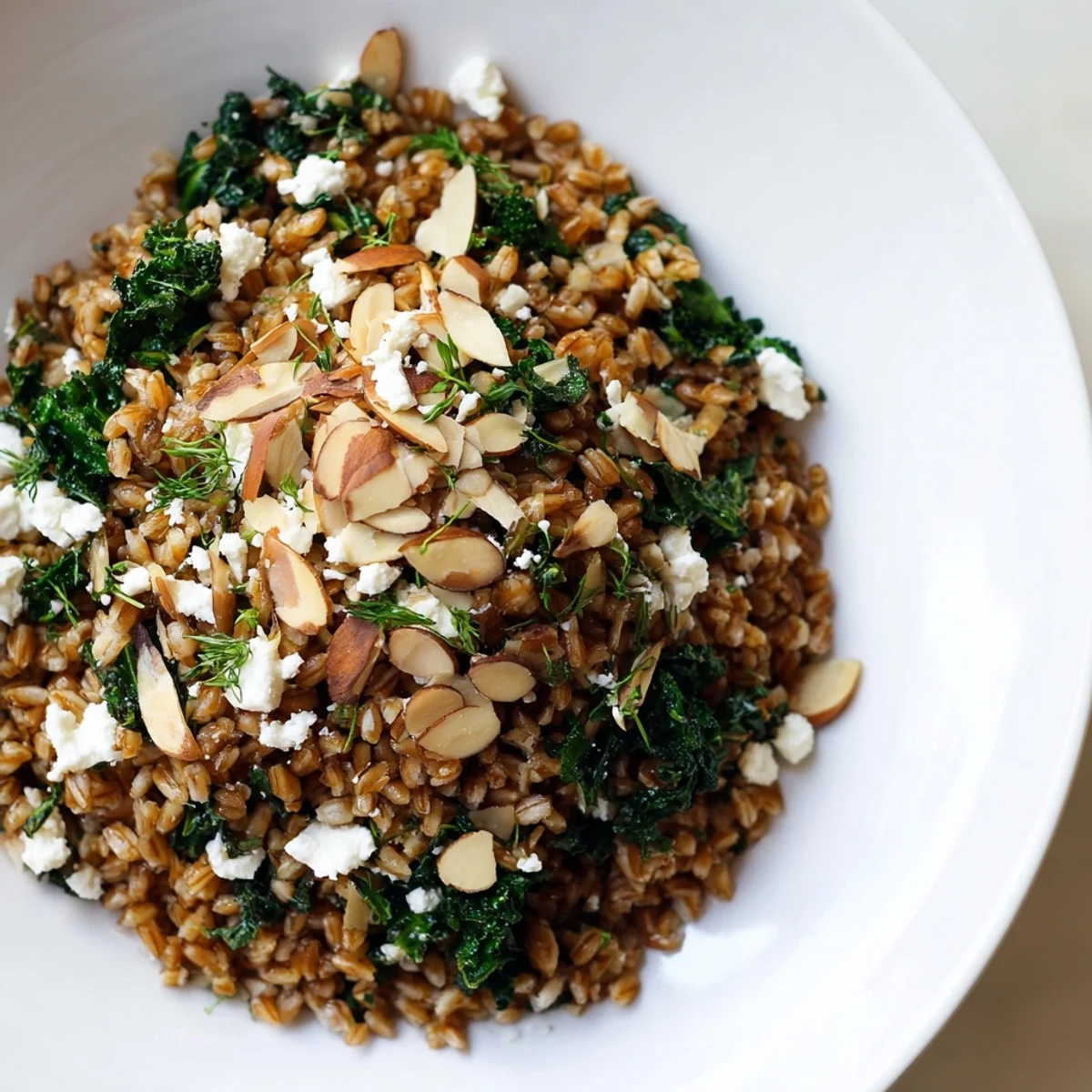 A nourishing bowl of warm farro and greens pilaf, with inviting aromas and crunchy almonds.