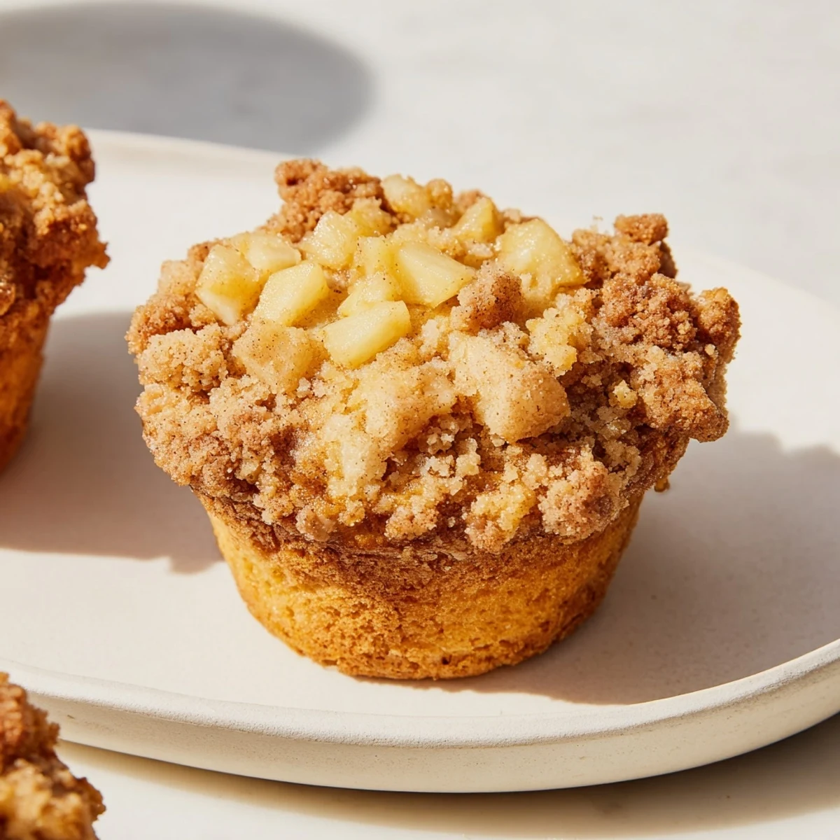 Golden-brown tasty apple muffins with a delicious, crunchy crumb topping, ready to eat.