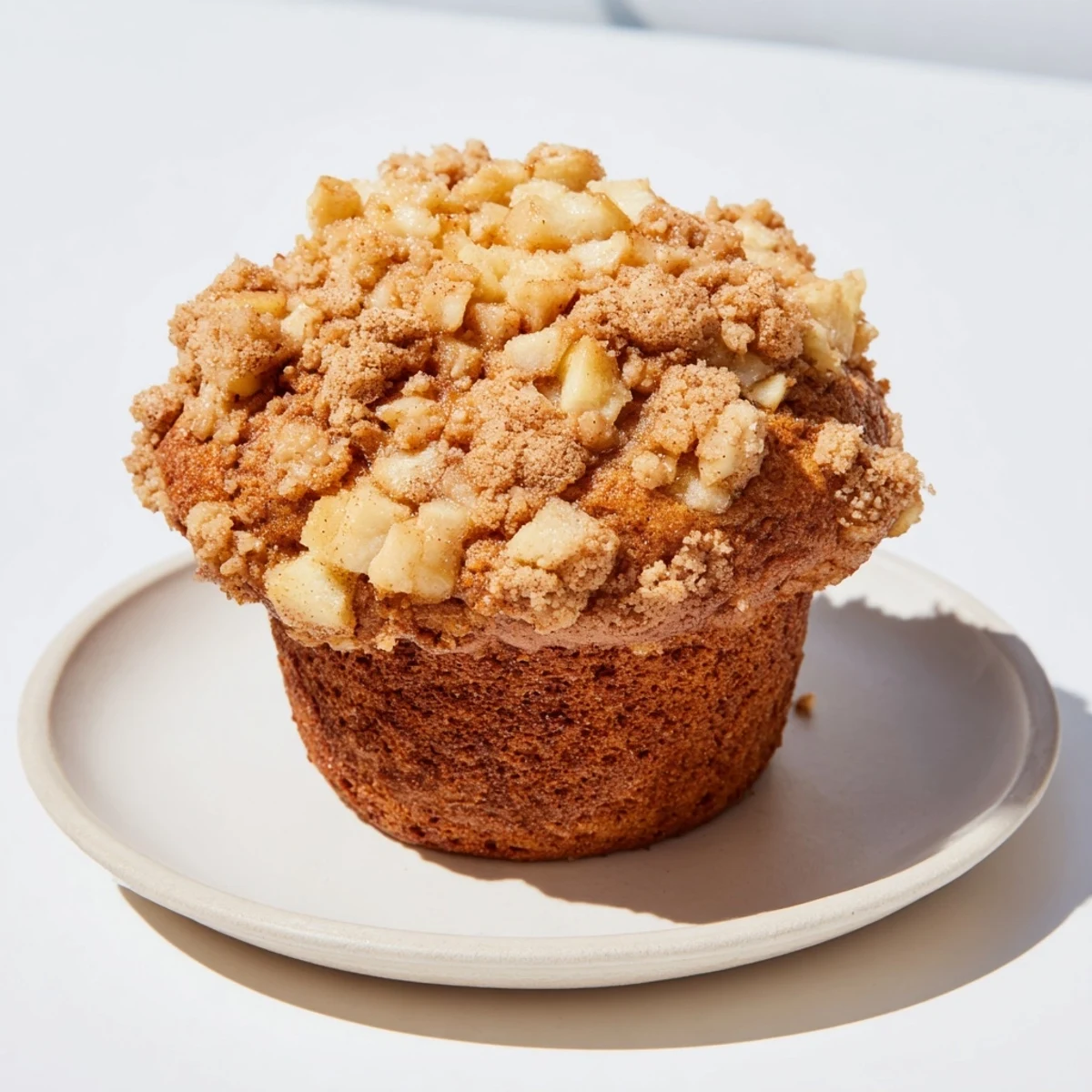 Freshly baked tasty apple muffins, featuring visible apple bits and a buttery crumble topping.