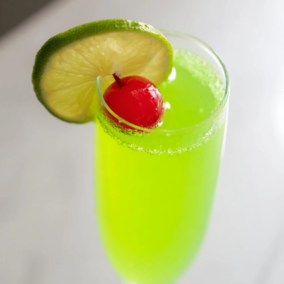 A close-up of a fizzy Quick Grinch Mimosa Mocktail, perfect for a non-alcoholic holiday treat with green hues.