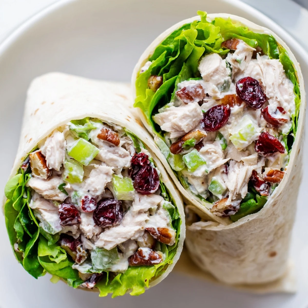 A close-up shot of a halved Cranberry Pecan Chicken Salad Christmas Wrap, overflowing with fresh ingredients.