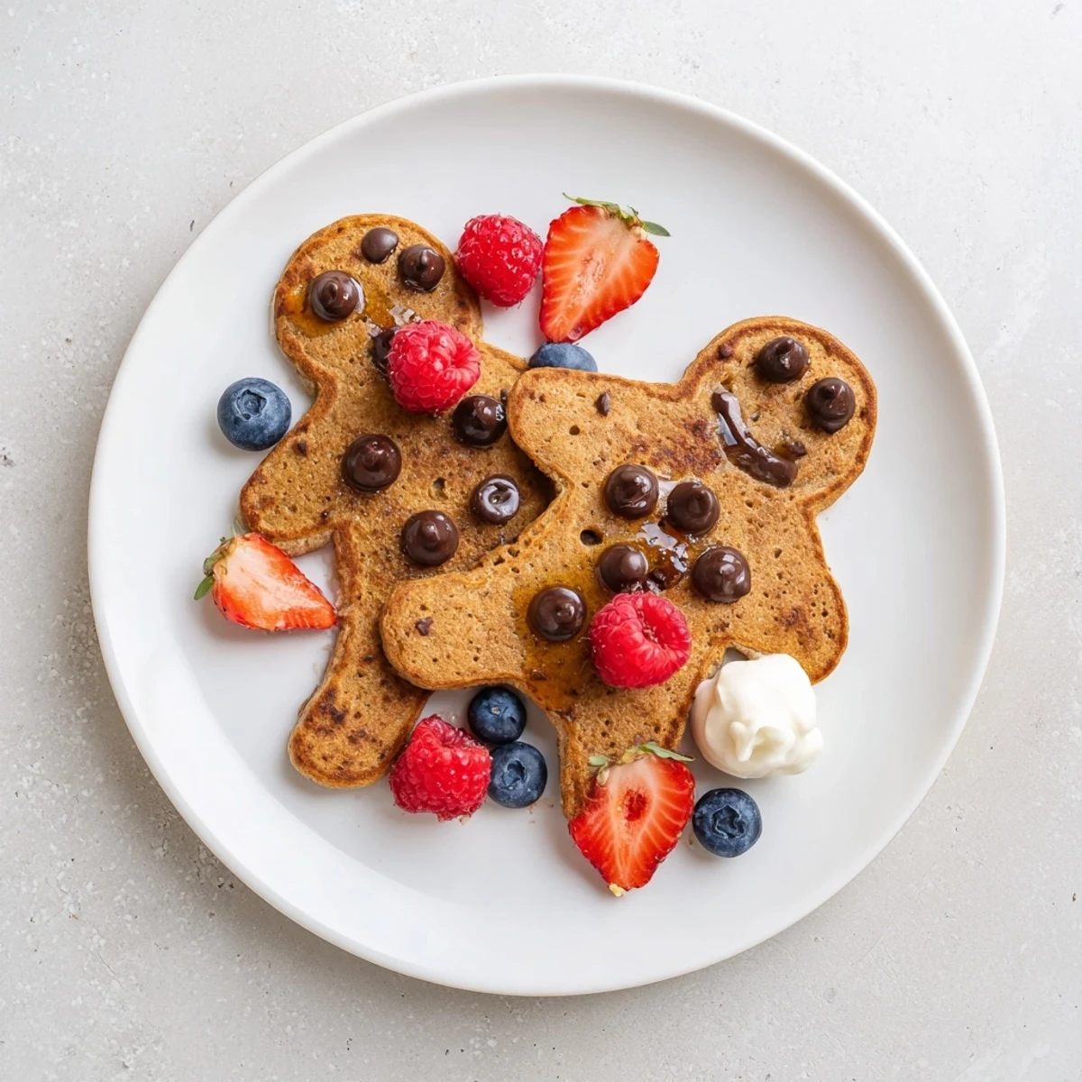 A colorful Gingerbread Boy Berry Board, featuring golden pancakes, vibrant berries, and creamy yogurt.