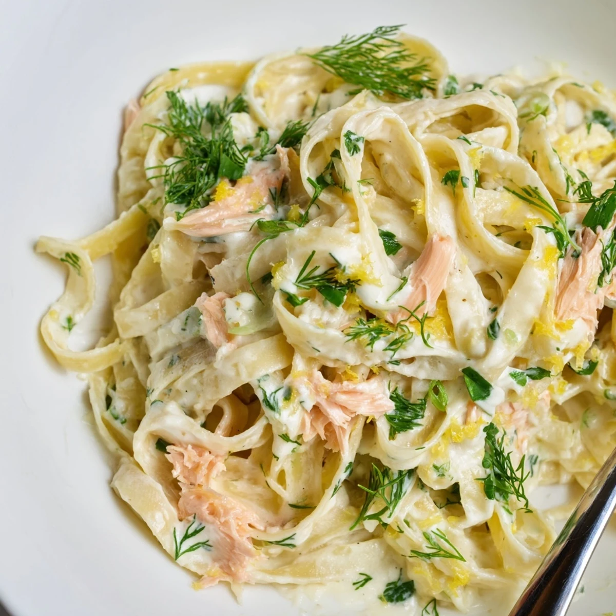 The Best Creamy Salmon Pasta served steaming in a skillet, fresh herbs and lemon zest sprinkled over a rich, creamy sauce.