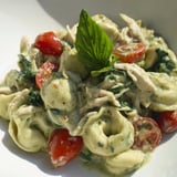 Steaming bowl of creamy pesto tortellini skillet served alongside crusty bread and a glass of white wine for a cozy family dinner.  
