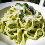 A bowl of Creamy Green Pea Alfredo, featuring fettuccine coated in a velvety green sauce, garnished with fresh basil and grated Parmesan.