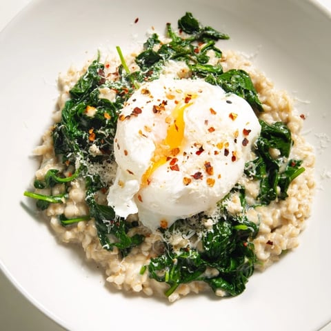 Oatmeal with spinach features a perfectly poached egg, creamy oats, and vibrant green spinach for breakfast.