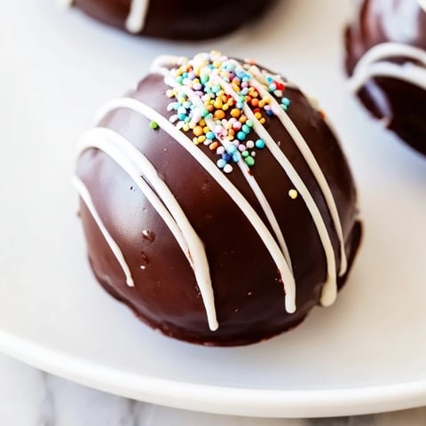 A mug brimming with creamy, dissolving Hot Chocolate Bombs, topped with colorful sprinkles.