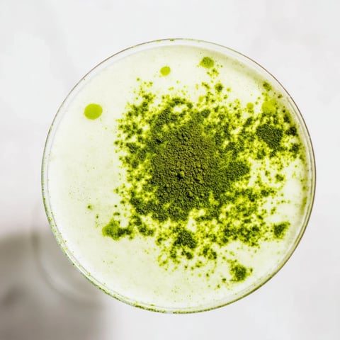Creamy Matcha Martini cocktail in a chilled glass, garnished with matcha powder, offering a delightful sip.