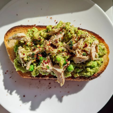Smashed pea and chicken toast features creamy mashed peas and shredded chicken on golden, crisp rustic bread.