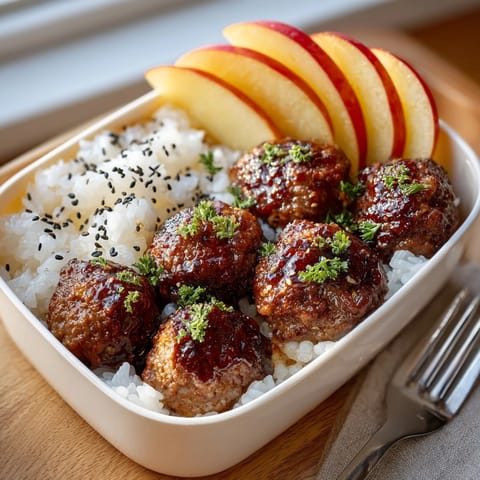 Tender cream soda BBQ meatballs shine next to fluffy rice and refreshing apple wedges, a fun bento.