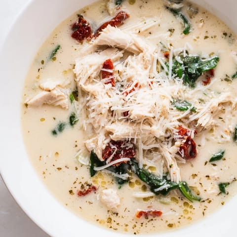 A pot of simmering Tuscan Chicken Soup with tender shredded chicken, vibrant spinach, and creamy herb-infused broth.  