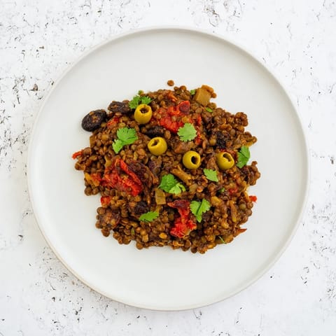 A vibrant skillet of Cuban-Inspired Lentil Picadillo features tender lentils, diced carrots, and a sprinkle of fresh cilantro.  