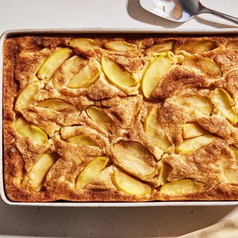Freshly baked Dutch apple cake with tender cinnamon-spiced apples and a golden crumb topping, served fresh from the oven.