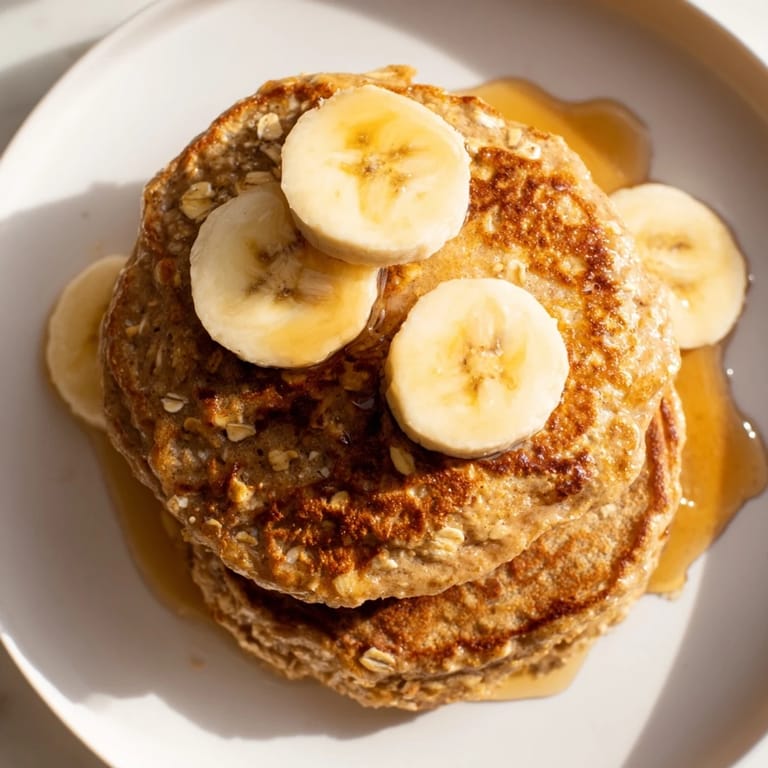 Warm, appetizing banana oat pancakes beside fresh berries, ready for a sweet, nutritious breakfast.