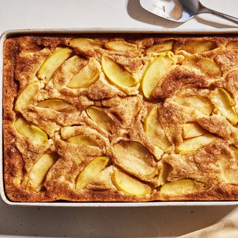 Freshly baked Dutch apple cake with tender cinnamon-spiced apples and a golden crumb topping, served fresh from the oven.